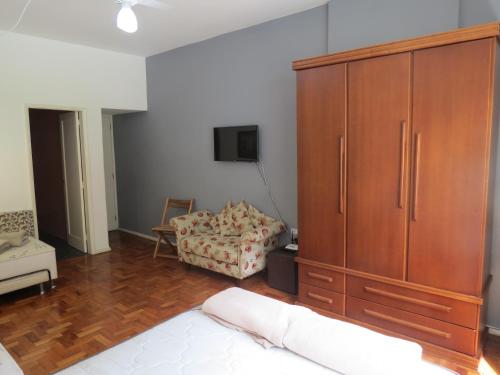 a bedroom with a large wooden cabinet and a couch at FLAT 201 in Petrópolis