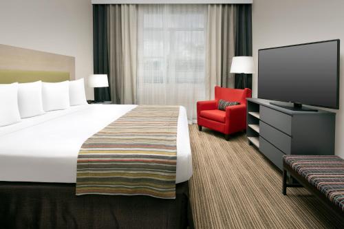 a hotel room with a large bed and a red chair at Country Inn & Suites by Radisson, Houston Intercontinental Airport East, TX in Humble