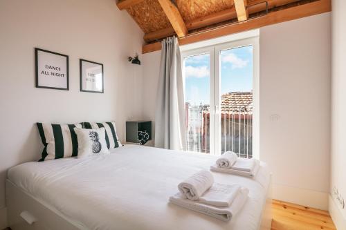 a bedroom with a large white bed with towels on it at Indulge Porto Flats in Porto