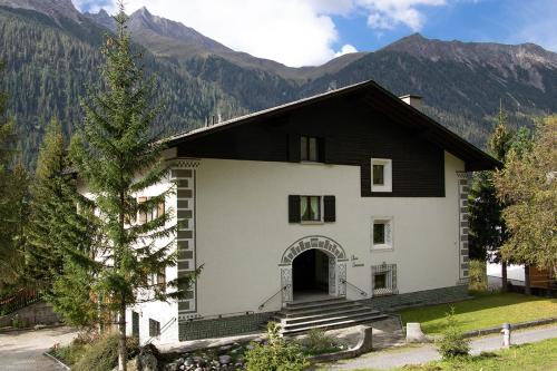 Une grande maison blanche avec des montagnes en arrière-plan dans l'établissement Chesa Dominium, à Bergün