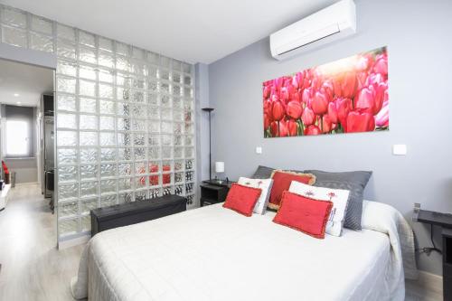 マドリードにあるChueca Apartmentの白いベッドと壁に絵画が飾られたベッドルーム1室