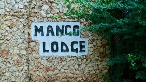 a stone wall with a sign that saysamed lodge at Mango Lodge MSAMBWENI in Kisimachande