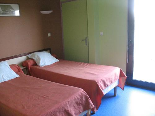 Cette chambre d'hôtel comprend 2 lits avec des draps rouges. dans l'établissement HOME DU BUISSON Hôtel des Familles, à Isle