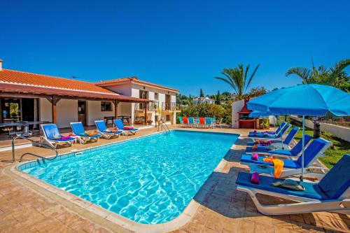 a pool with chairs and umbrellas next to a house at Androniki Luxury Villa Sea Views Pool BBQ WiFi A/C in Polis Chrysochous