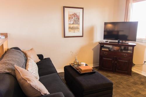 a living room with a couch and a flat screen tv at Vineyard Court Designer Suites Hotel in College Station