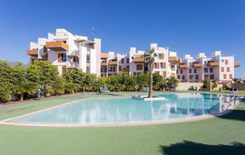 une grande piscine en face d'un grand bâtiment dans l'établissement Sea View Apartment in El Médano with pool & private parking space, à El Médano