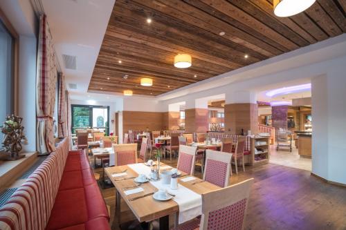 un restaurante con techos de madera, mesas y sillas en Hotel Untersberg en Sankt Leonhard