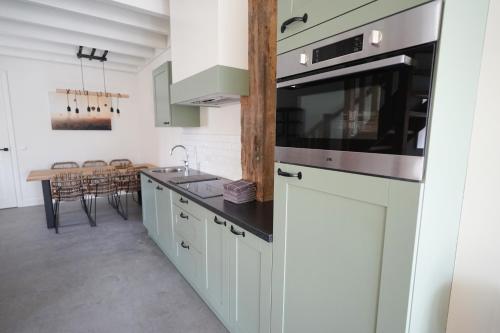 a kitchen with white cabinets and a stove top oven at 't Veldehof in Domburg