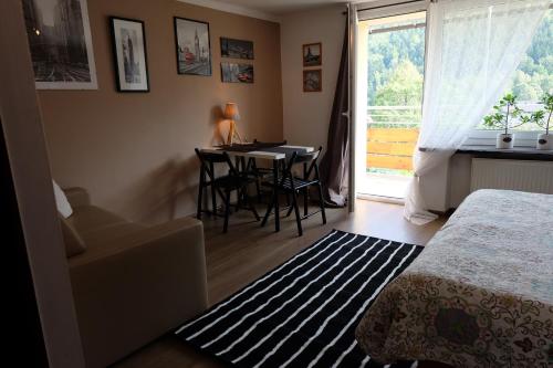 a bedroom with a bed and a table and a window at Willa Pod Aniołem - Pokoje Gościnne & Apartamenty z widokiem na góry in Szczyrk