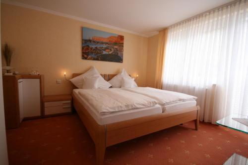 a bedroom with a bed with white sheets and a window at Aqua Marina in Helgoland