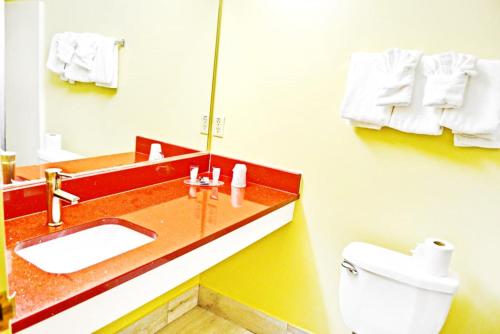 a bathroom with a sink and a toilet and a mirror at Flagship Inn & Suites in Groton