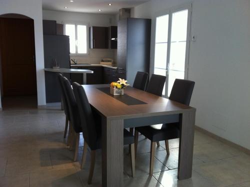 une salle à manger avec une table en bois et des chaises noires dans l'établissement La Fleur de Sel, à La Flotte