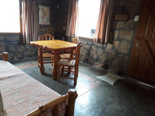 a wooden table and two chairs in a room at Alauri Ñire in Huinganco