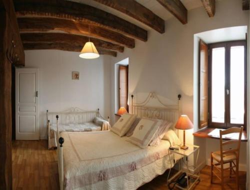 a bedroom with a bed and a desk and windows at Auberge Saint Hernin in Pluherlin