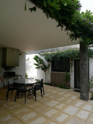 eine Terrasse mit einem Tisch, Stühlen und einem Baum in der Unterkunft Casa da Tapada - Grupo Casas Vale do Lima in Ponte de Lima