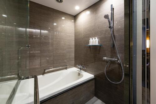 a bathroom with a bath tub and a shower at The Royal Park Canvas - Ginza 8 in Tokyo