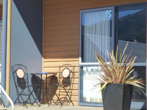 a patio with chairs and tables and a window at Hanmer Springs Scenic Views Motel in Hanmer Springs