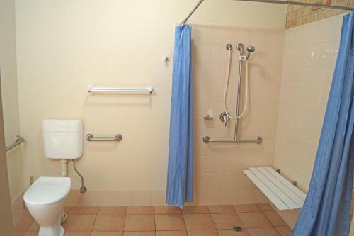 uma casa de banho com um WC e um chuveiro com cortinas azuis em Emeraldene Inn & Eco-Lodge em Hervey Bay
