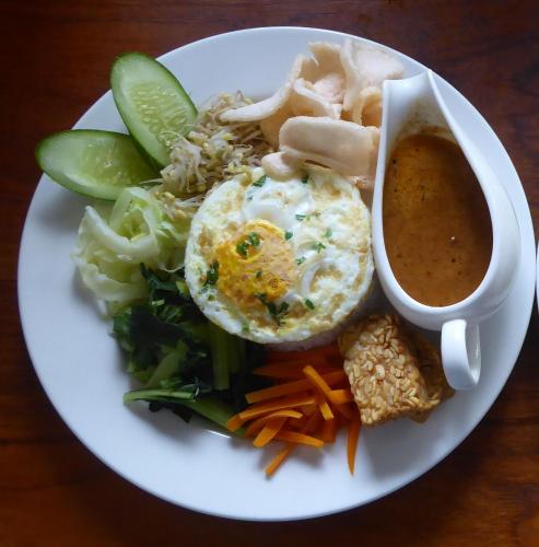 a plate of food with an egg and vegetables and a cup of soup at Rumah Kita Villa/hotel in Kalibaru