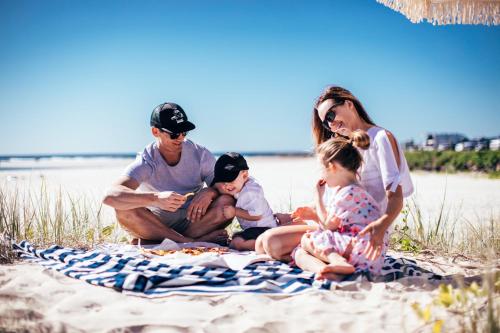 a family sitting on a blanket on the beach at Nobby Beach Holiday Village in Gold Coast