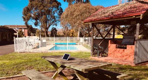 a picnic table with a laptop on it next to a pool at Alfred Motor Inn in Ballarat