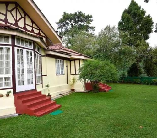 a house with a green lawn in front of it at The Heritage Club - Tripura Castle Hotel and Spa in Shillong