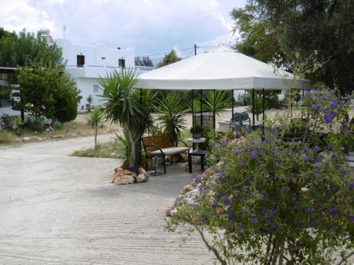 a patio with a white umbrella and some flowers at Skyros Panorama Studios in Skiros