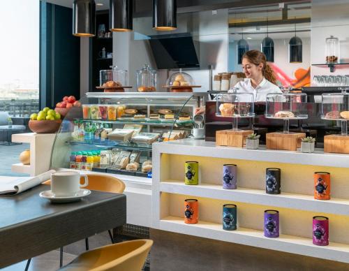a woman is behind the counter of a bakery at WestSide Residences by Rotana in Istanbul