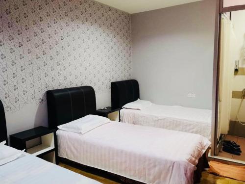 a hotel room with two beds and a mirror at Home Inn Hotel in Ipoh