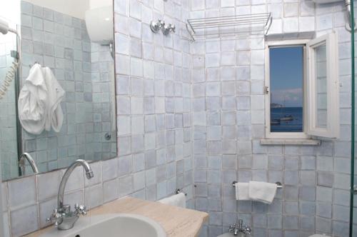 un bagno con lavandino, specchio e finestra di Hotel Gennarino A Mare a Ponza