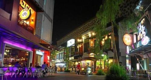 una calle de la ciudad por la noche con mesas y sillas en Cihampelas Homestay, en Bandung