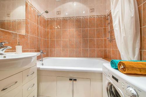 W łazience znajduje się wanna, umywalka i pralka. w obiekcie Apartment on Karl Marx Street w Mińsku