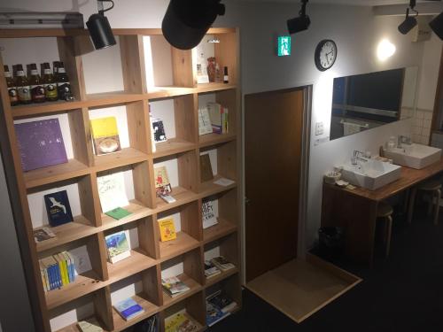 une chambre avec une étagère, un bureau et une horloge dans l'établissement Tomarigi Hostel Cafe Bar, à Kōchi