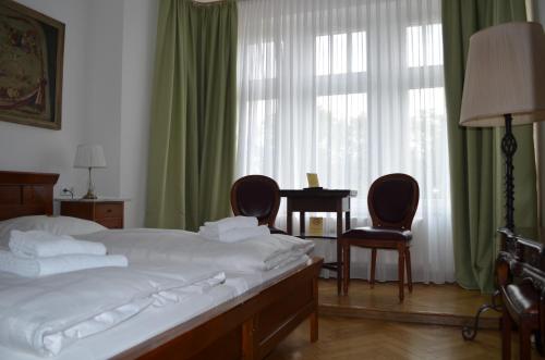 a bedroom with a bed and two chairs and a table at Jahrhunderthotel Leipzig in Leipzig