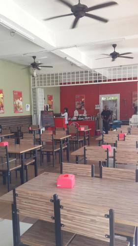 a classroom with wooden tables and chairs and a piano at Daisyinn Budget Hotel Kuala Terengganu in Kampong Gong Badak