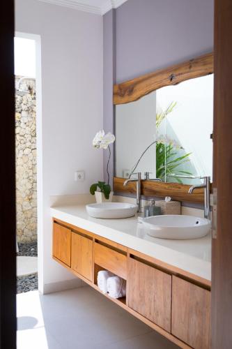 a bathroom with two sinks and a mirror at Silversand Villa in Tanah Lot