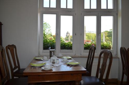 a dining room table with chairs and a table and windows at Jahrhunderthotel Leipzig in Leipzig