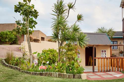 a house with palm trees in front of a yard at First Group Club Hacienda in Shelly Beach