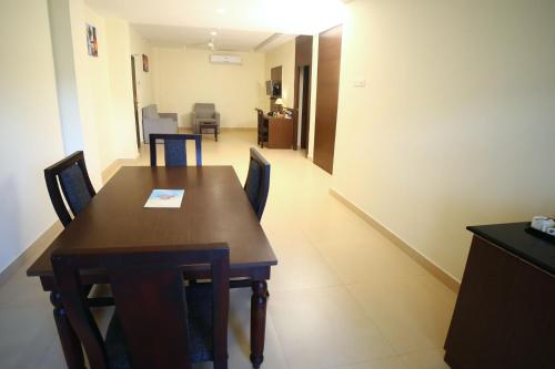 a dining room with a wooden table and chairs at Hotel Yamuna in Adūr