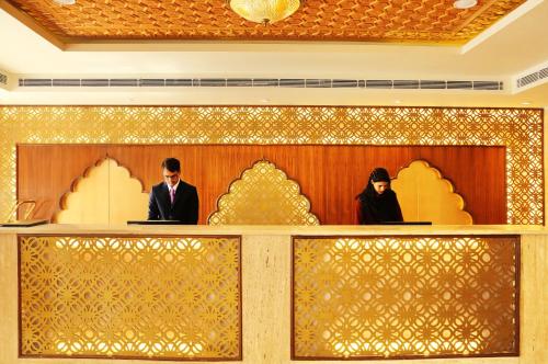 a man and a woman standing at a counter in a lobby at Regenta Central Srinagar, Rajbagh in Srinagar