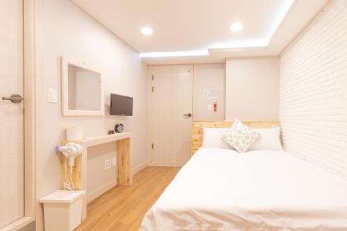 Dawoo House 1 in Hongdae في سول: غرفة نوم بيضاء مع سرير وتلفزيون