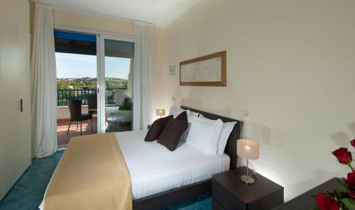 a bedroom with a white bed and a balcony at Portoverde Beach Apartments in Misano Adriatico