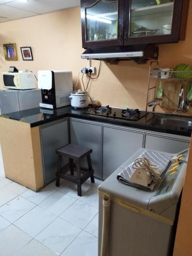 a kitchen with a counter with a stove and a stool at De La Homestay in Alor Setar