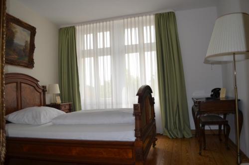 a bedroom with a bed and a window with green curtains at Jahrhunderthotel Leipzig in Leipzig