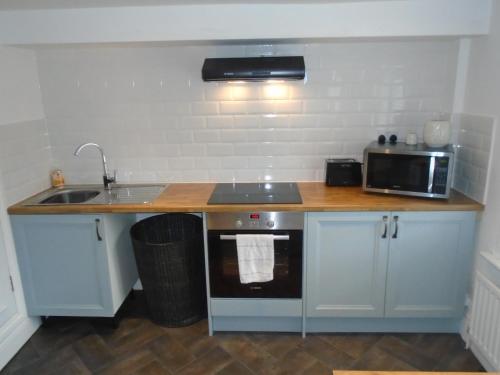 una pequeña cocina con fregadero y microondas en Kenilworth Cosy Castle View Apartment, en Kenilworth