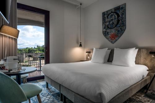 a bedroom with a bed and a desk and a window at SOWELL HOTELS Les Chevaliers in Carcassonne