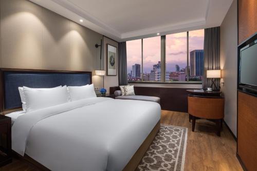 Un dormitorio con una gran cama blanca y una ventana en Yiwu Kasion Purey Hotel, en Yiwu