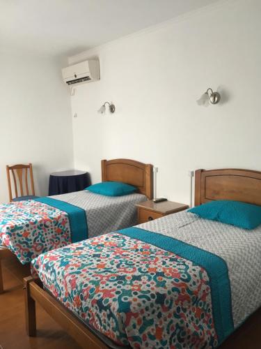 2 Betten in einem Zimmer mit blauer und grüner Bettwäsche in der Unterkunft Hospedaria O Castelo in Portel
