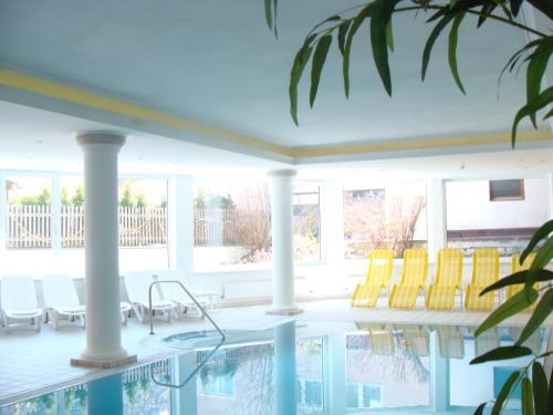 a swimming pool with yellow chairs on a porch at Hotel Erika in Nauders