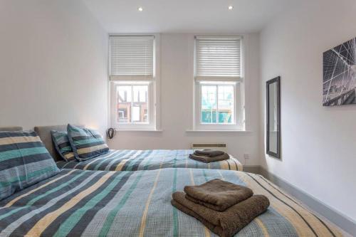 1 Schlafzimmer mit 2 Betten und 2 Fenstern in der Unterkunft Spacious Central Chic Apartment - Simply Check In in Winchester